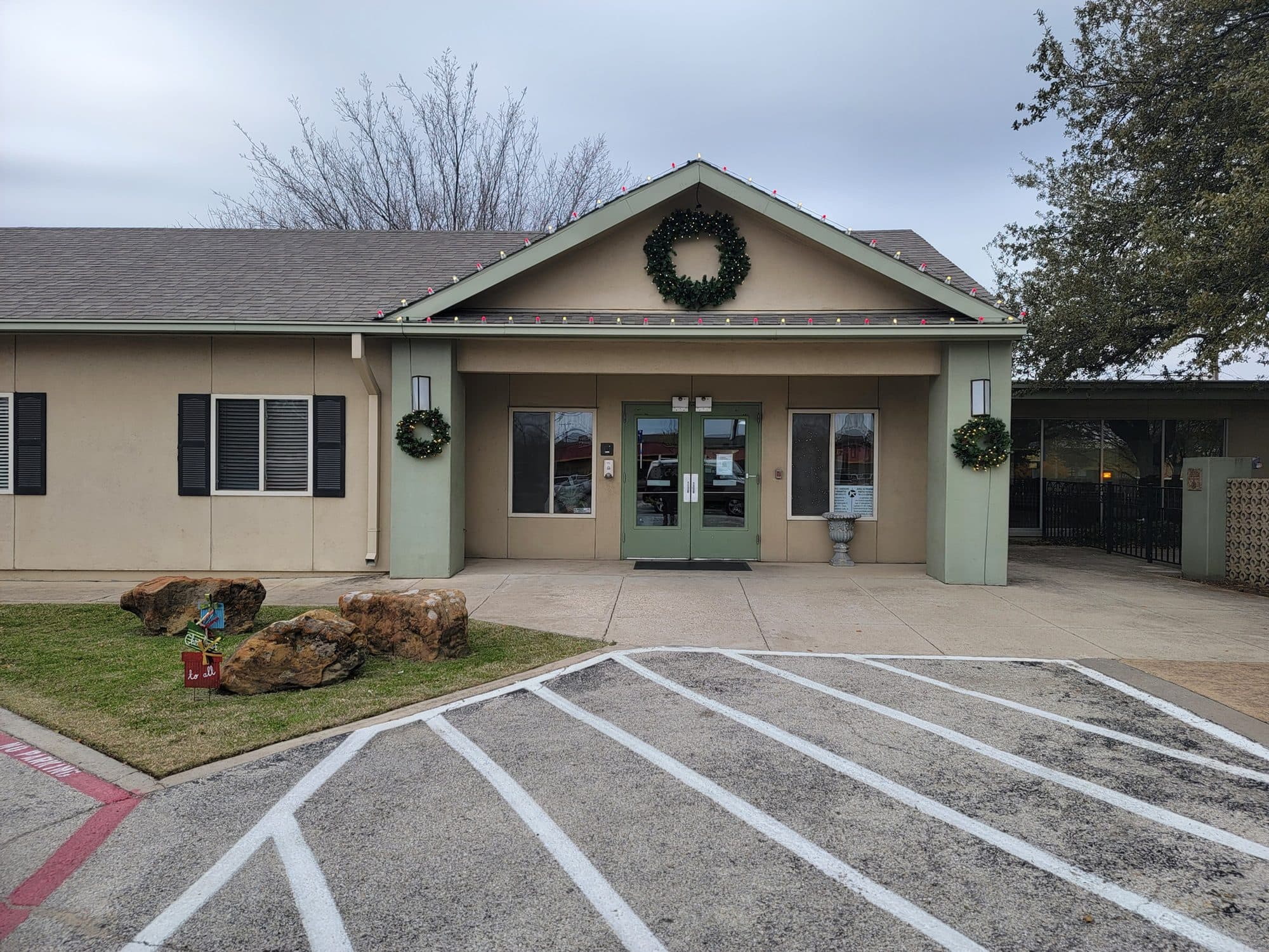 Greenbrier Healthcare Center entrance in Arlington with a candy cane outline on the front peak, a 48-inch pre-lit wreath on the gable and two pre-lit wreaths beside the doors