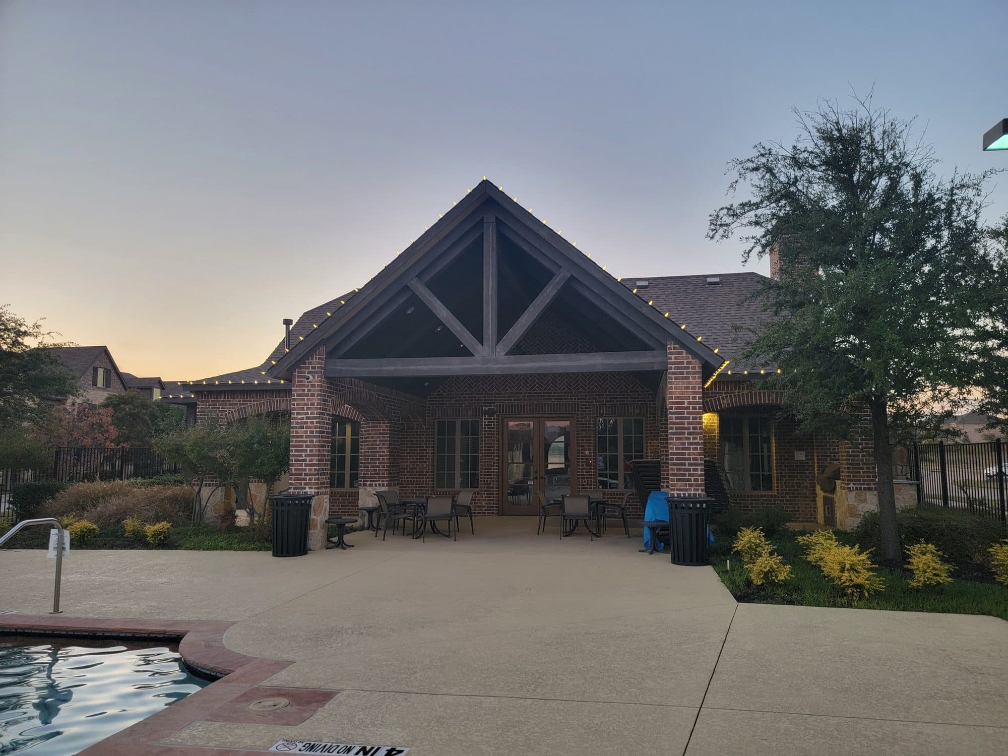 The pool-side patio of the Mustang Park clubhouse in Carrollton with warm white lights along the gable and rooflines