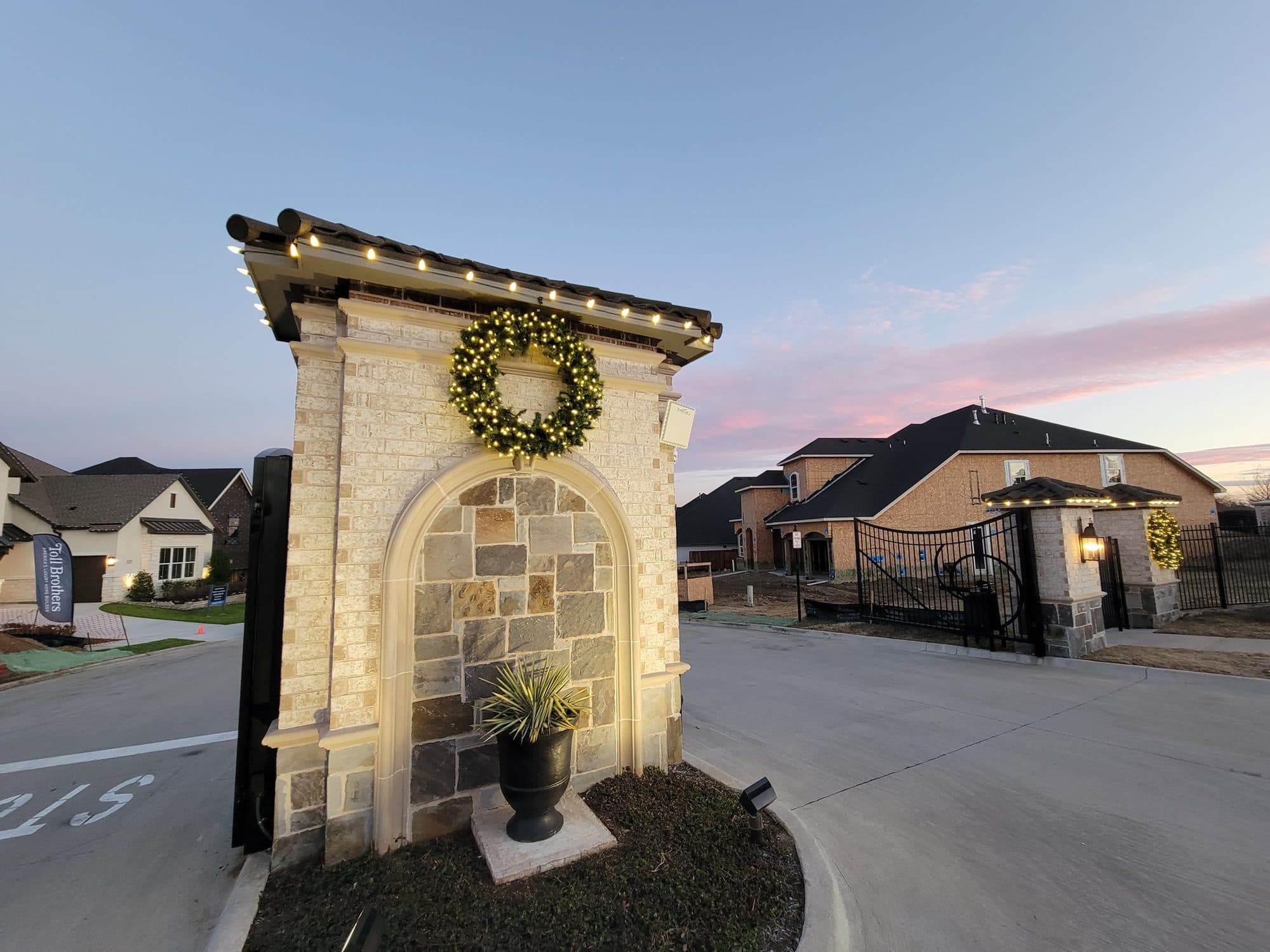 Paradiso Valle HOA entrance monument in McKinney outlined in warm white C9 bulbs with a lit pre-lit wreath